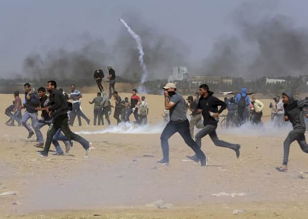 Palestinian protesters run for cover from teargas fired by Israeli troops near the border fence, east of Khan Younis, in the Gaza Strip, Tuesday, May 15, 2018. Israel faced a growing backlash Tuesday and new charges of using excessive force, a day after Israeli troops firing from across a border fence killed 59 Palestinians and wounded more than 2,700 at a mass protest in Gaza. (AP Photo/Adel Hana)