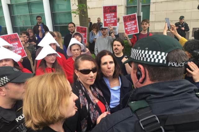 Campaigners intervene after police try to lead away one of the three women (centre with sunglasses) who publicly took an abortion pill during a demonstration outside Belfast's Crown and High Courts, where counter-demonstrations were held by both sides of the Northern Irish abortion argument. Northern Ireland is the only part of the UK where the procedure is not legal.