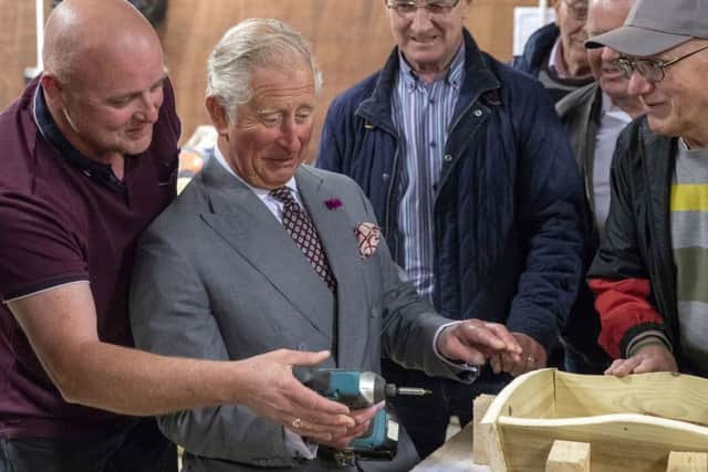 The Prince of Wales uses a power driver to put screws into an ornamental wheelbarrow during a visit to the Owenkillew Community Centre in Gortin