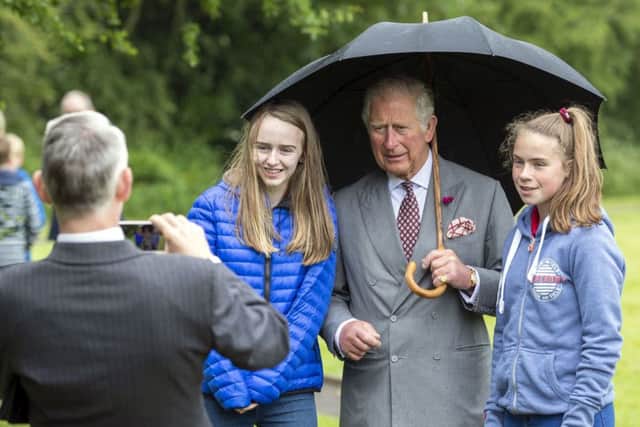 The Prince of Wales shelters under an umbrella as he has his picture takem with local children during a visit to the Owenkillew Community Centre in Gortin