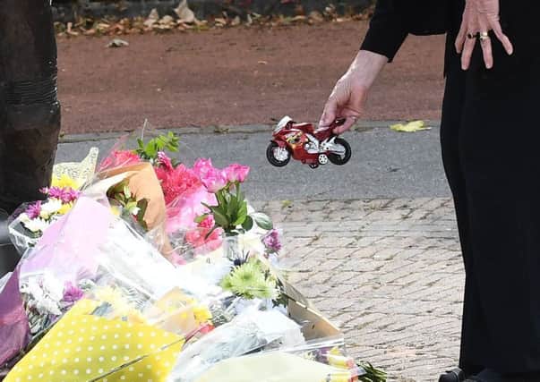 A mourner leaves a toy motorbike among the floral tributes to William Dunlop at the Dunlop Memorial Garden in Ballymoney on Sunday