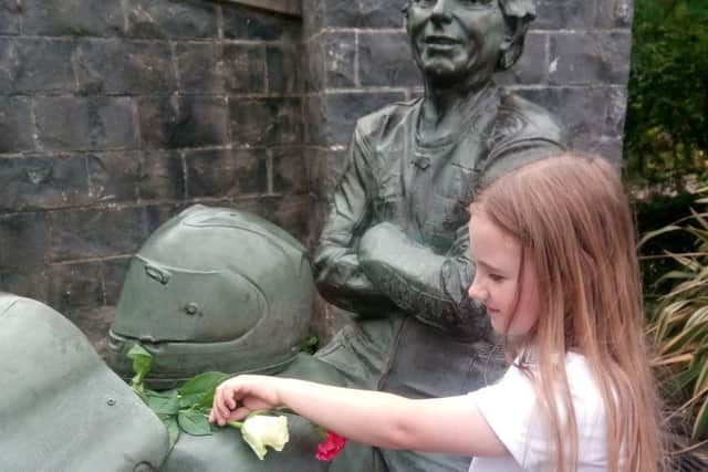 Mia, nine, lays a single white rose in memory of William Dunlop at the statue of his uncle, Joey Dunlop, in Ballymoney
