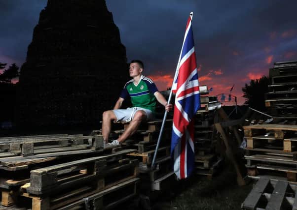 One of the young men who built the bonfire at Ballymacash in Lisburn keeps watch at the site ahead of the Eleventh Night celebrations