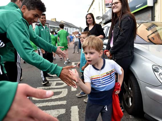 A young onlooker high fives visiting footballers during the opening ceremony parade in Coleraine for SuperCupNI 2018