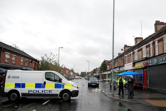A police van is parked across the area of Claremont Road, Moss Side, Manchester