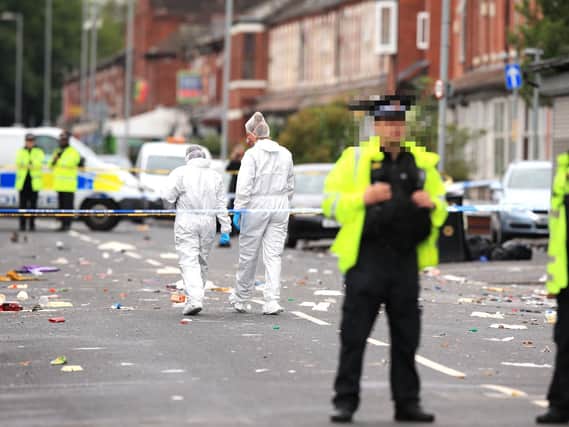 Police officers and forensics at the scene in Claremont Road, Moss Side, Manchester, where several people have been injured after a shooting