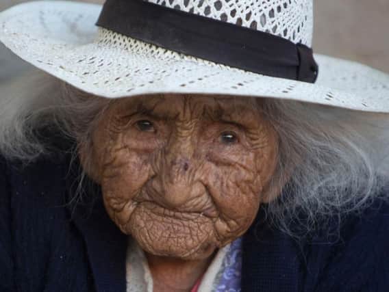 In this Aug. 23, 2018 photo, 117-year-old Julia Flores Colque eyes the camera while sitting outside her home in Sacaba, Bolivia. Her national identity card says Flores Colque was born on Oct. 26, 1900 in a mining camp in the Bolivian mountains. At 117 and just over 10 months, she would be the oldest woman in the Andean nation and perhaps the oldest living person in the world.