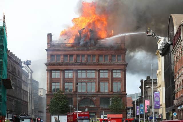 The fire raging on the top floor of Primark store in Belfast city centre on Tuesday, a firefighter trains a hose on the blaze. Later that day the blaze moved down the building, ultimately engulfing all of it. Photo: Liam McBurney /PA Wire