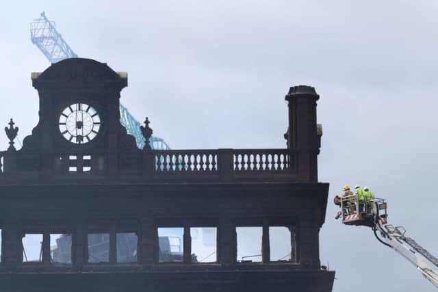 A firefighter and engineers inspecting the charred facade of the Primark store in the historic five-storey Bank Buildings in Belfast city centre, following the collapse of the internal floors in a devastating fire which broke out on Tuesday
