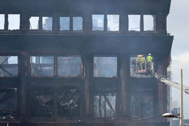 A firefighter and engineers inspecting the charred facade of the Primark store in the historic five-storey Bank Buildings in Belfast city centre, following the collapse of the internal floors in a devastating fire which broke out on Tuesday