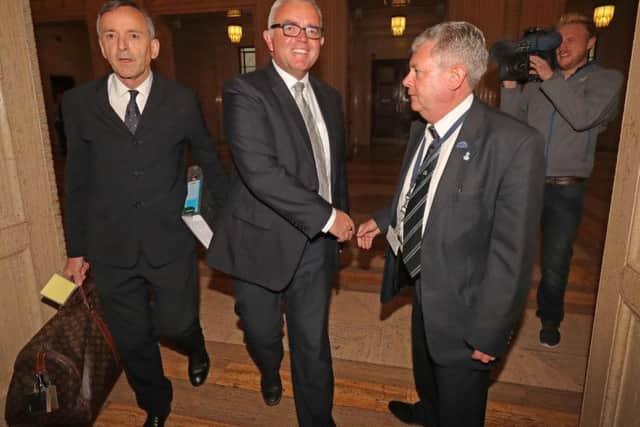 Solicitor Denis Moloney and his client, former DUP minister Jonathan Bell (centre) shake hands with and unnamed security official as they arrive at the RHI inquiry at Stormont Parliament buildings in Belfast