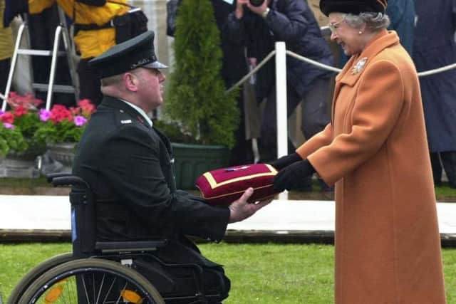 The Queen presents the George Cross to disabled RUC officer Paul Slane in 2000. "Just consider the despicable proposal as part of the HIU, designed to entrap ex RUC/PSNI officers and destroy their reputation even if they are not guilty of a criminal offence," writes Robin Swann. Picture Steve Wilson Pacemaker