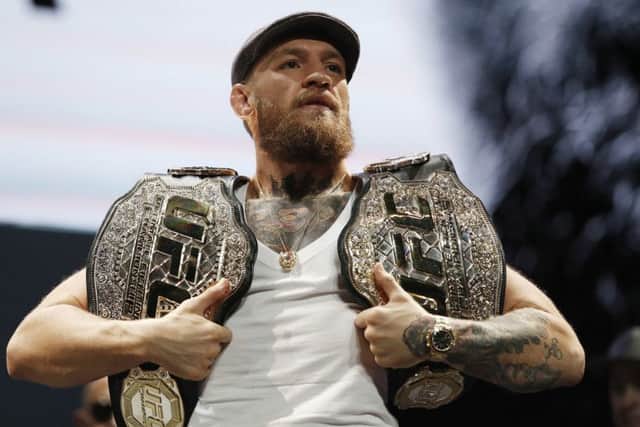 Conor McGregor holds up belts
