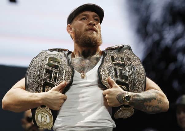 Conor McGregor holds up belts