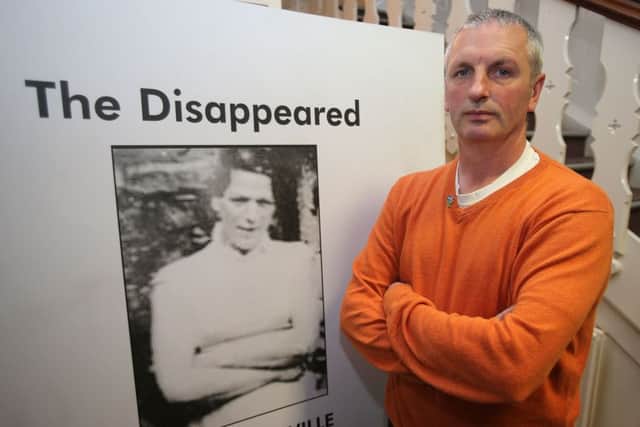 Michael McConville beside a picture of his mother Jean, who was abducted and murdered by the IRA in 1972