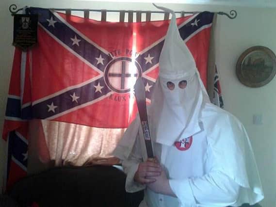 Undated handout file photo issued by West Midlands Police of a picture allegedly showing Adam Thomas wearing the hooded white robes of the Ku Klux Klan (KKK) whilst brandishing a machete in front of a KKK flag at his home in Oxfordshire.