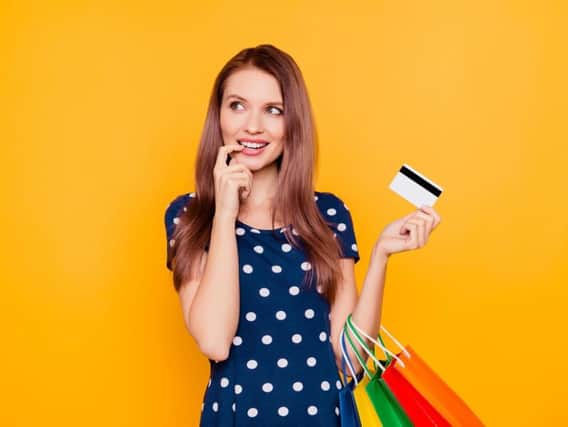 A generic photo of a woman holding a credit card and shopping bags.