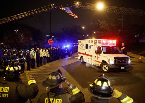 Police and firefighters salute as an ambulance arrives at the medical examiner's office carrying the body of Chicago Police Department Officer Samuel Jimenez, who was killed during a shooting at Mercy Hospital earlier in the day, Monday, Nov. 19, 2018, in Chicago. (Armando L. Sanchez/Chicago Tribune via AP)