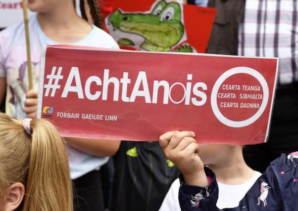 A child on the Falls Road holds up a sign supporting an Irish language act