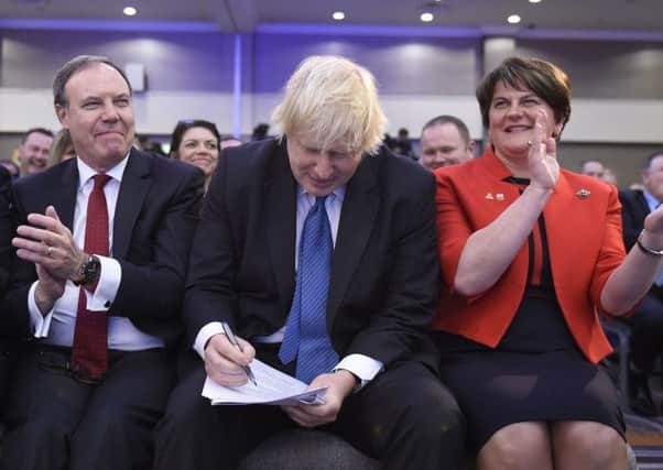 (left to right) Deputy Leader of the DUP Nigel Dodds, Boris Johnson, making notes to his speech, and DUP Party leader Arlene Foster during the DUP annual conference at the Crown Plaza Hotel in Belfast