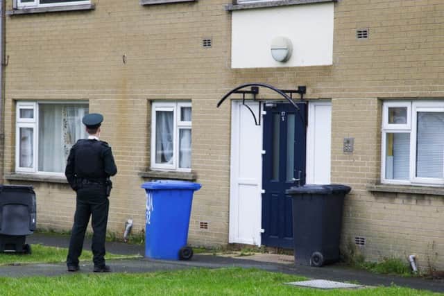 A police officer outside a block of flats in Burrendale Park Road in Newcastle where the body of 29-year-old Padraig Fox was found