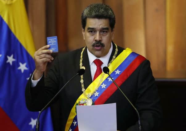 Venezuela's President Nicolas Maduro holds up a small copy of the constitution as he speaks during his swearing-in ceremony at the Supreme Court in Caracas, Venezuela, Thursday, Jan. 10, 2019