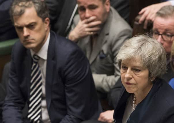 Chief whip Julian Smith, left, looks on as the Prime Minister Theresa May speaks in the crowded House of Commons in London after losing a vote on her Brexit plan on Tuesday. Moments earlier, he had bent over Mrs May's ear to inform her of the disastrous defeat. Photo: UK Parliament/Mark Duffy/PA Wire