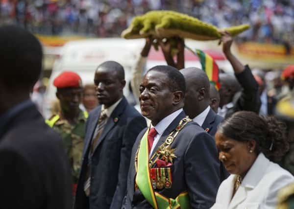 Zimbabwe's President Emmerson Mnangagwa, centre, known as "The Crocodile", and his wife Auxillia, right, leave as a supporter holds a stuffed crocodile behind, after the presidential inauguration ceremony in the capital Harare, Zimbabwe Friday, Nov. 24, 2017. Mnangagwa was sworn in after Robert Mugabe resigned, ending his 37-year rule. (AP Photo/Ben Curtis)