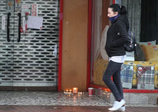 A woman walks past the shop doorway in Belfast city centre where the body of a homeless man was found last week. Lit candles were placed at the site in memory of the man. Pic Colm Lenaghan/Pacemaker
