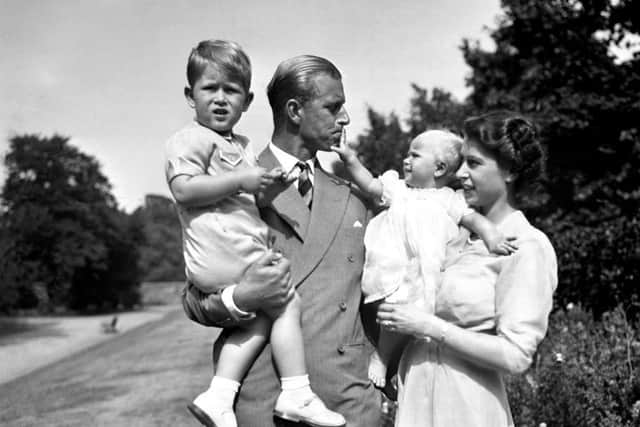 Princess Anne in the arms of Princess Elizabeth, with the Duke of Edinburgh, holding Prince Charles, in the grounds of Clarence House, their London residence.