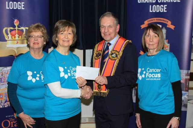 Past county grand master Stuart Brooker presents funds to volunteers representing Cancer Focus NI
