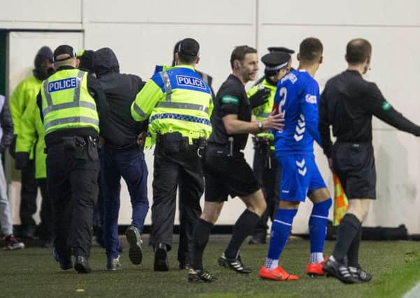 Rangers James Tavernier is pulled away from a fan that ran onto the pitch at half-time at Easter Road