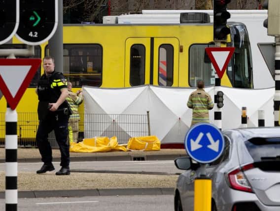 Rescue workers install a screen on the spot where a body was covered with a white blanket following a shooting in Utrecht, Netherlands