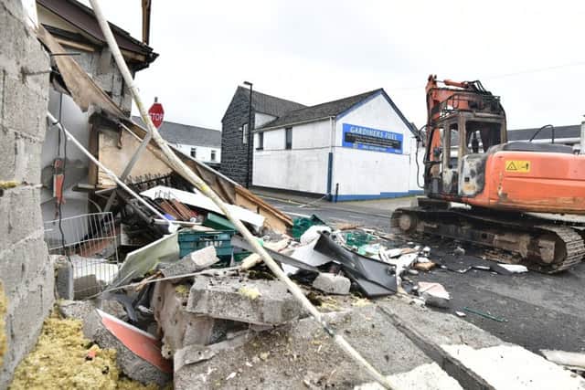 The burnt out digger sitting beside the rubble where it was used to rip an ATM out of a shop wall in Ahoghill. 
Photo: Colm Lenaghan/Pacemaker Press
