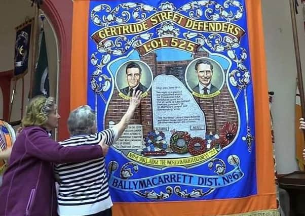 Mrs Kathleen McCurrie reaching out to touch the image of her late husband on the Gertrude Street Defenders banner