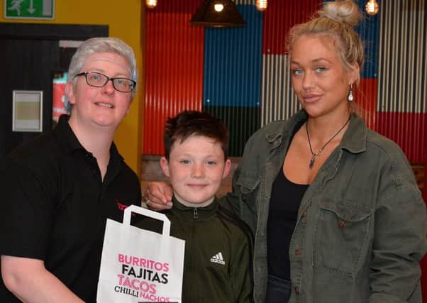 Paula Toner, manager of Boojum Restrurant, presents Long Tower Primary School pupil, Téirnan McCready, aged nine, with a voucher for one year of free food from the local Strand Road restaurant. Included in the picture is Téirnan's mum Céire