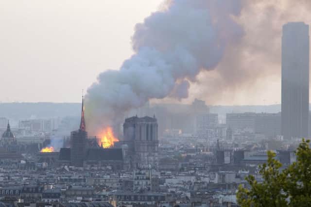 Notre Dame cathedral is burning in Paris, Monday, April 15, 2019. Massive plumes of yellow brown smoke is filling the air above Notre Dame Cathedral and ash is falling on tourists and others around the island that marks the center of Paris. (AP Photo/Rafael Yaghobzadeh)