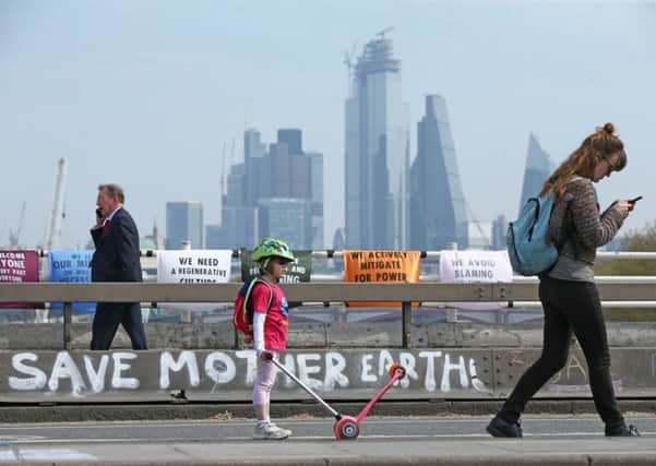People pass by the Extinction Rebellion demonstration on Waterloo Bridge, London, April 18, 2019, where protestors demanded real action on climate change