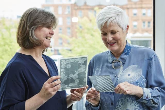 Barbara Dass and Trish Belford with the plates used to keep track of designs in the linen mill in Donaghcloney