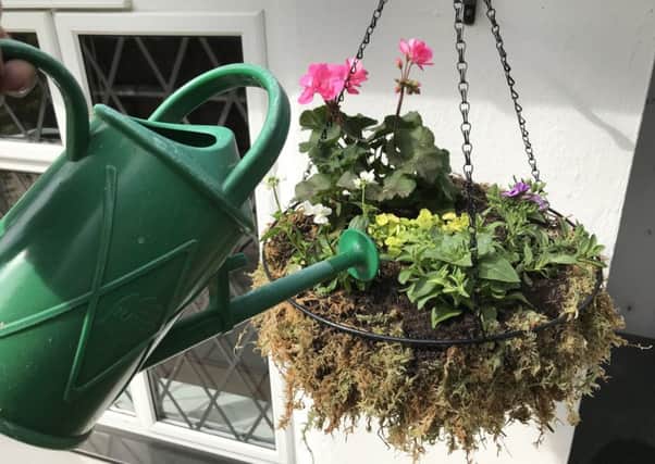 Watering a hanging basket.
Picture credit: Hannah Stephenson/PA.