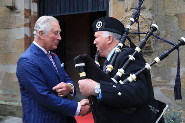 Charles chats to a piper at the entrance of Brownlow House