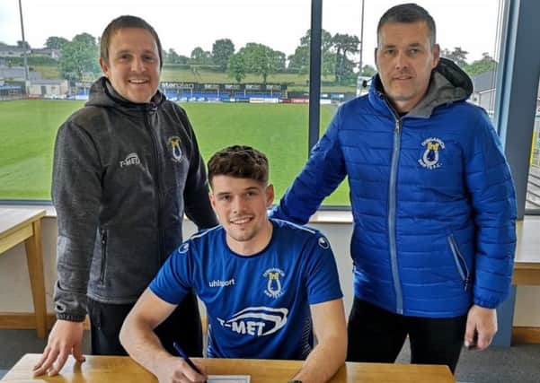 Callum Byers puts pen to paper at Dungannon Swifts as Chris Wright (left, assistant manager) and Keith Boyd (chairman) look on. Pic courtesy of Dungannon Swifts.