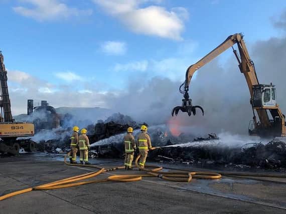 Fire crews, assisted by McKenzies crane drivers, dampen down the smouldering pile of scrap metal. Pic: McKenzies (NI) Ltd