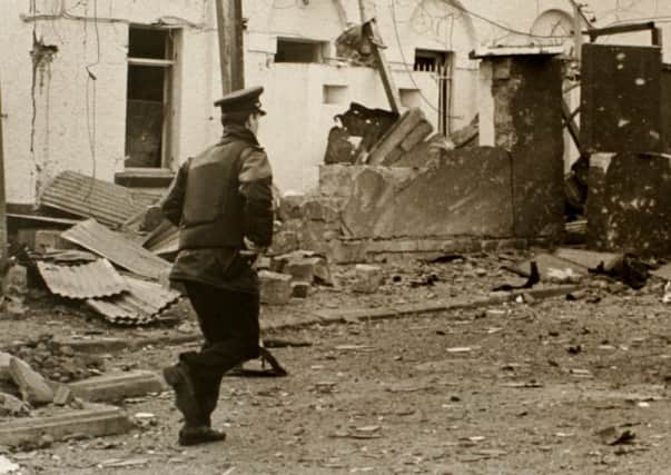 A lone RUC policeman runs into the scene of the IRA bomb attack at Randalstown