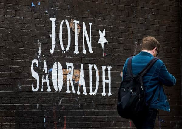 A man walks past graffiti in the North Belfast area with the writing "Join Saoradh", an unregistered far-left political party formed by dissident republicans. Photo credit: Liam McBurney/PA Wire