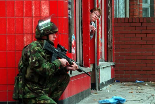 Operation Banner. A soldier guards colleagues building a 'Peace Wall' in North Belfast during the 1990s .