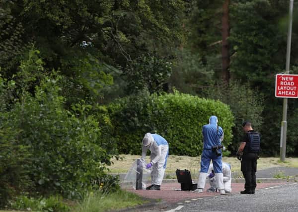An ammunition technical officer and forensic officers in Tullygally Road, Craigavon, Co Armagh after an explosive device used by dissident republicans in a failed bid to kill police officers was discovered. Photo: Brian Lawless/PA Wire