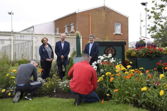 A show garden created by prisoners in Maghaberry has won a National Trust Gold Award. Using a range of recycled materials and bedding plants grown in the maximum security facility, 14 prisoners built the garden which features a train - the Maghaberry Flyer - and track, reflecting their journey from incarceration to release. Pictured in the garden with prisoners at work are from right to left, Ronnie Armour, Director General of the Northern Ireland Prison Service, Richard Whiting, Belfast Met horticulture trainer and Tammi Peek, National Trust Volunteering and Partnerships Manager. Picture: Michael Cooper