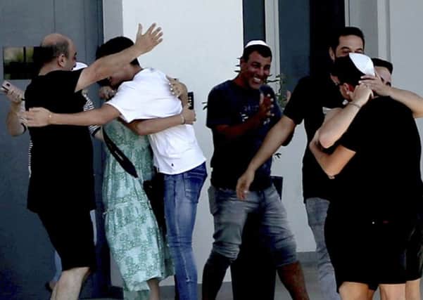 An Israeli teenager is embraced by relatives after being released by police in Paralimni, Cyprus, Sunday, July 28, 2019. He was one of seven Israeli teenagers who were detained as suspects in the alleged rape of a 19-year-old British woman. She was arrested and faced a public nuisance charge. (AP Photo/Petros Karadjias)