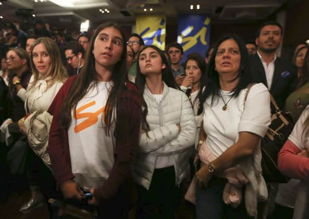 Supporters of the peace deal signed between the Colombian government and rebels of the Revolutionary Armed Forces of Colombia, FARC, listen to results of a referendum on a peace deal in 2016, which was narrowly rejected by the people. (AP Photo/Fernando Vergara).